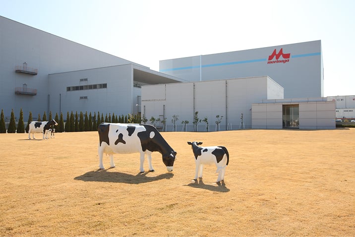 工場を背景に牛3頭の模型が点在している写真