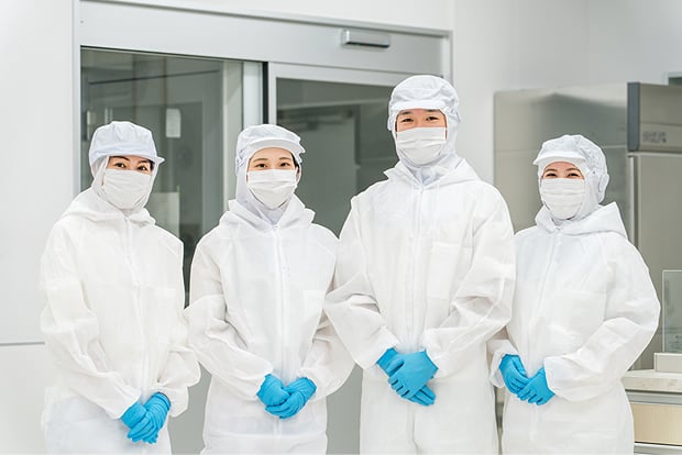 衛生白衣を着用した4人がこちらを向いて笑顔で立っている写真